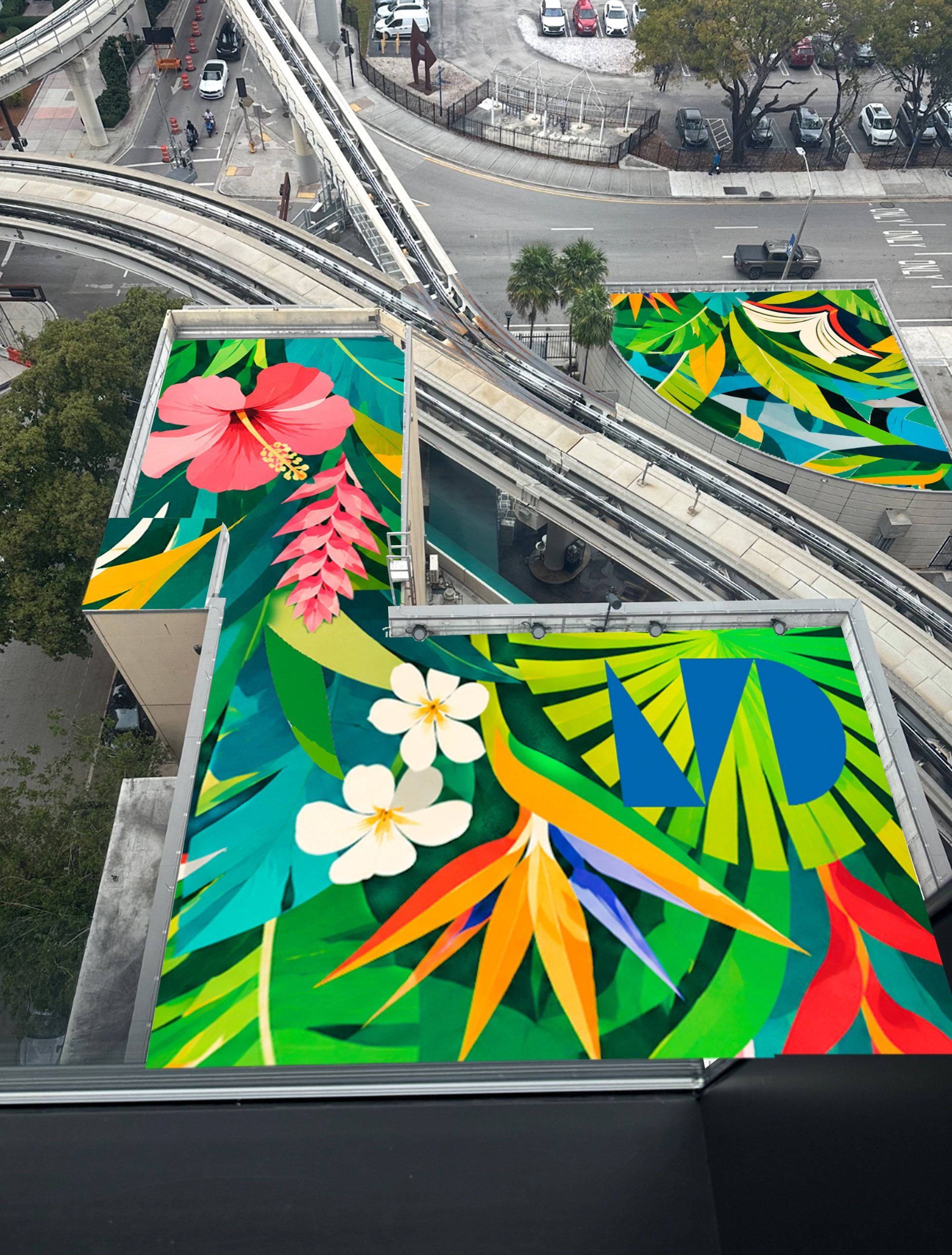 Miami Dade College Wolfson Campus roofs beside the Metromover, covered in a tropical composition of hibiscus, bird of paradise and palm leaves with the college's MD mark